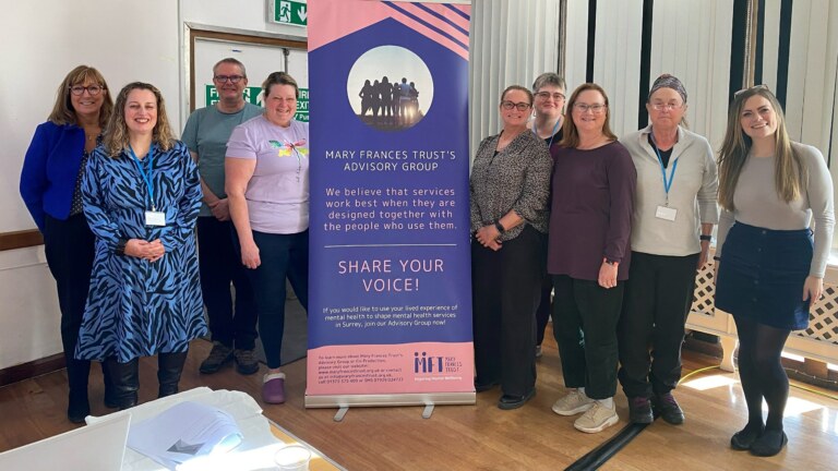 Group photo of our Advisory Group at their Away Day standing and smiling next to the MFT Advisory Group banner